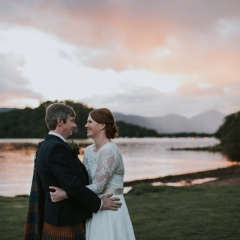 A bride and groom hugging in the sunset on the shores of Loch Lomond