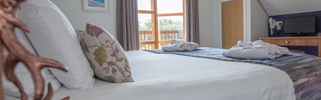 A double bedroom with doors open onto the balcony in a Diamond Lodge at Loch Lomond Waterfront