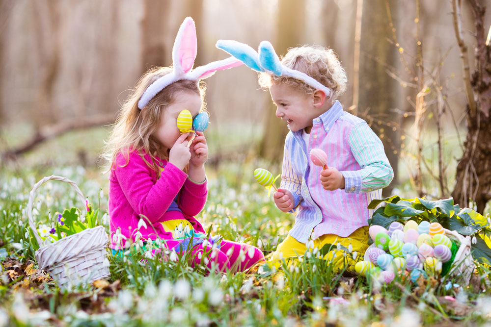 Children on Easter egg hunt in blooming spring garden