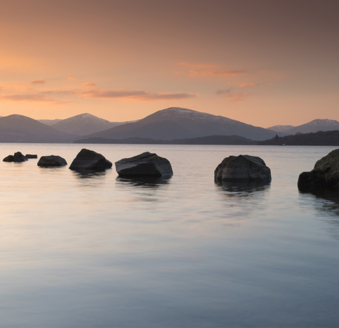Milarochy Bay at Loch Lomond with a row of stones going out into the water. One of the best winter walks in Scotland.