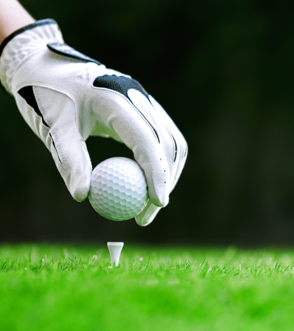 Hand putting golf ball on tee in golf course