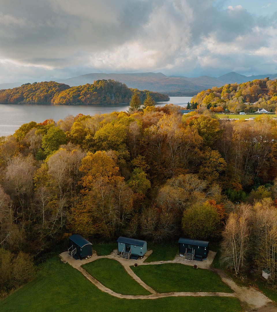 Three Shepherd's Huts with Loch Lomond in the background at Loch Lomond Waterfront luxury lodges in Balmaha