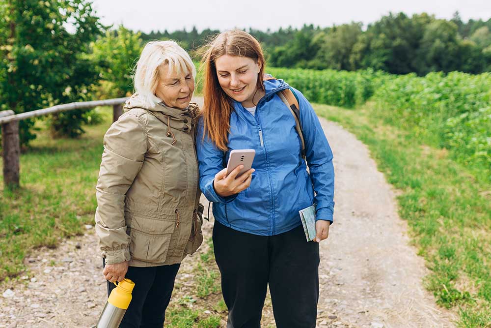 Two ladies looking at their phone whilst on a hike.