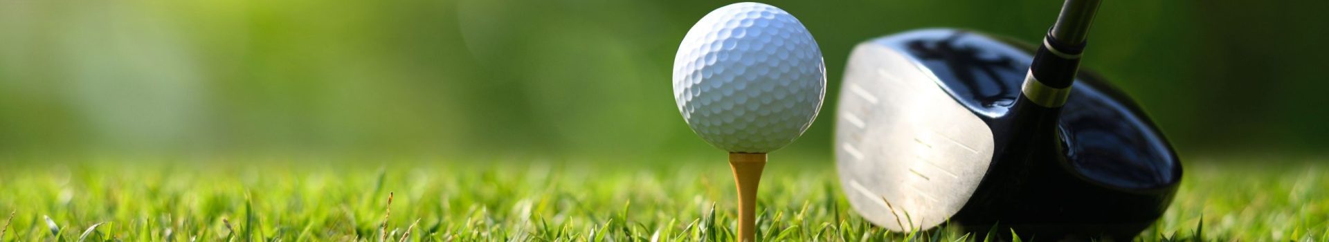 Close-up golf ball on tee with golf drivers at golf course.