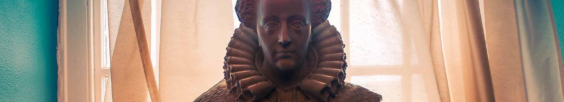 Statue of Mary Queen of Scots in front of curtains.