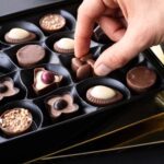 A person picking from a fancy box of chocolates.