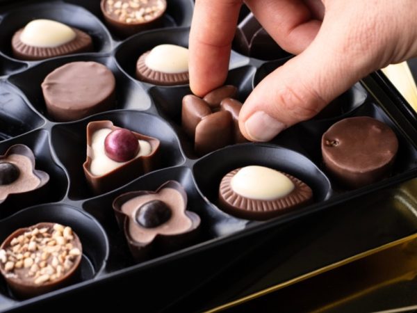 A person picking from a fancy box of chocolates.