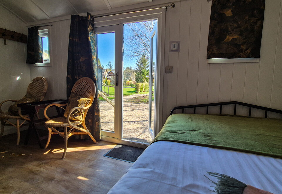 The view outside through the double doors from the bed in a Shepherd&#039;s Hut at Loch Lomond Waterfront
