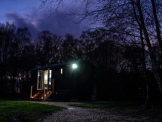 A Shepherd&#039;s Hut at Loch Lomond Waterfront lit up at night