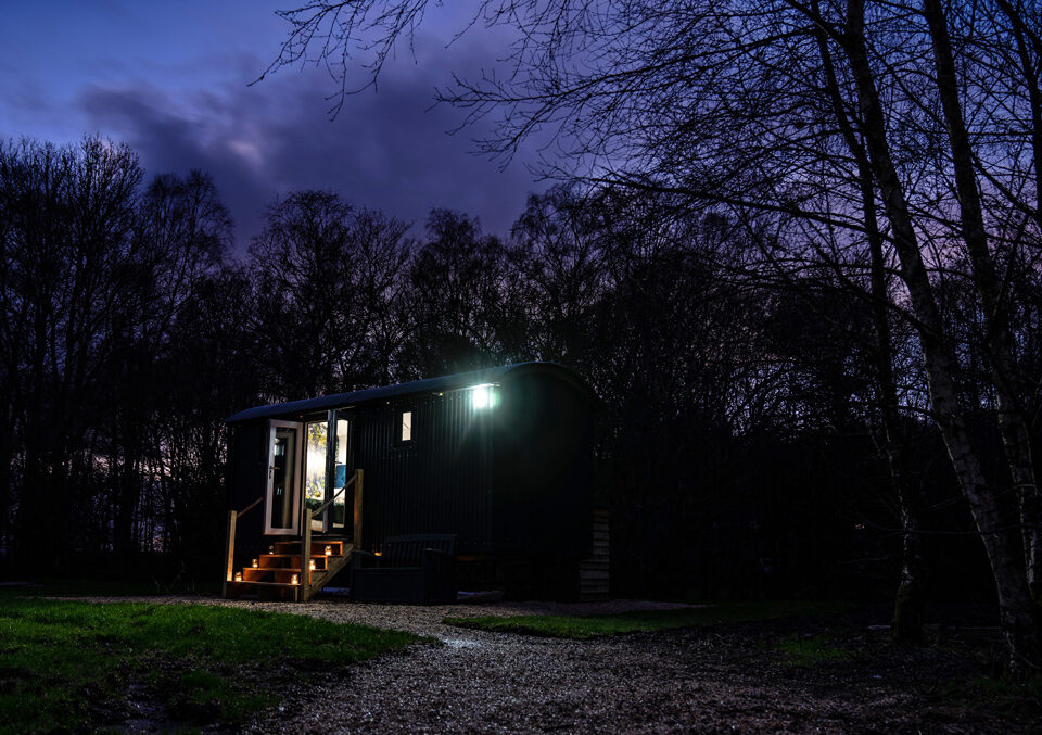 A Shepherd&#039;s Hut at Loch Lomond Waterfront lit up at night