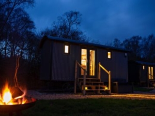 A Shepherd&#039;s Hut at Loch Lomond Waterfront with a campfire outside