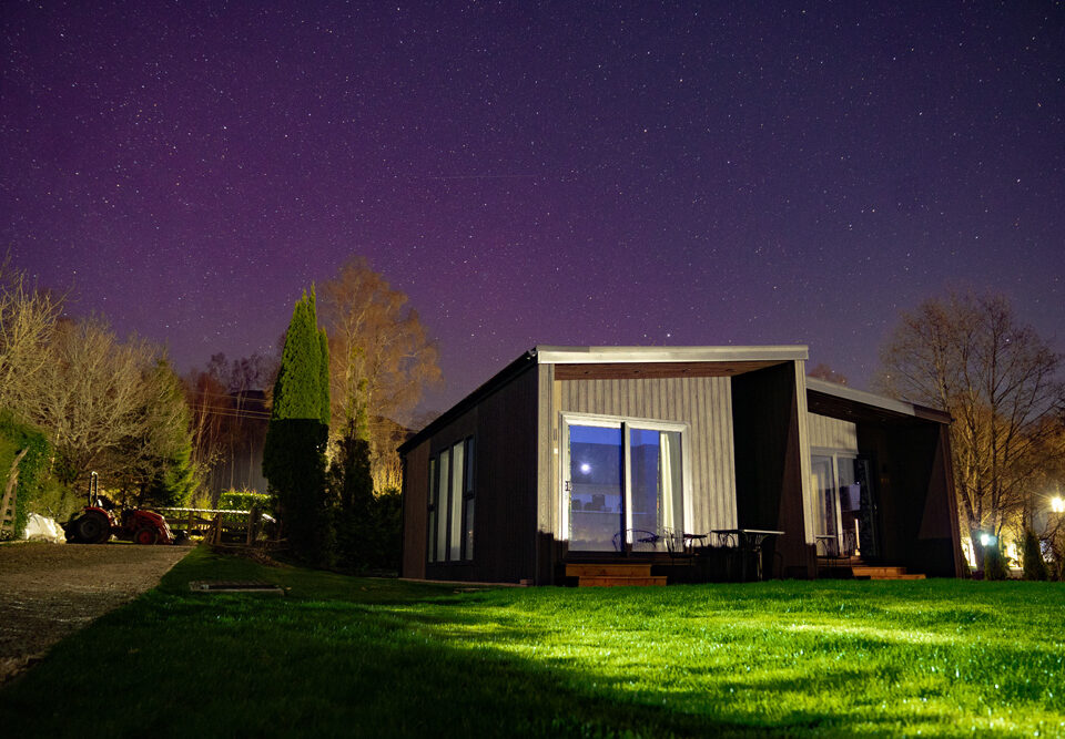 A Studio Lodge at night at Loch Lomond Waterfront with the Northern Lights in the sky.