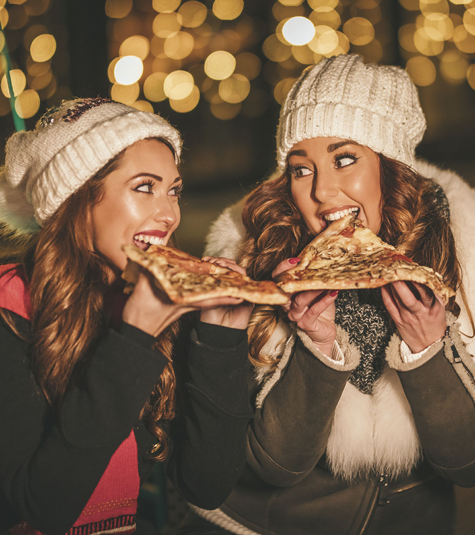 Girls eating pizza in warm winter clothing