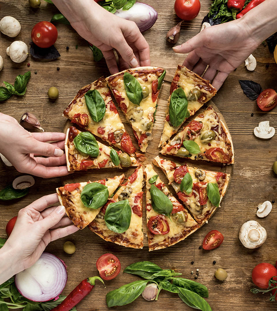 A sliced pizza with hands around it taking a slice each