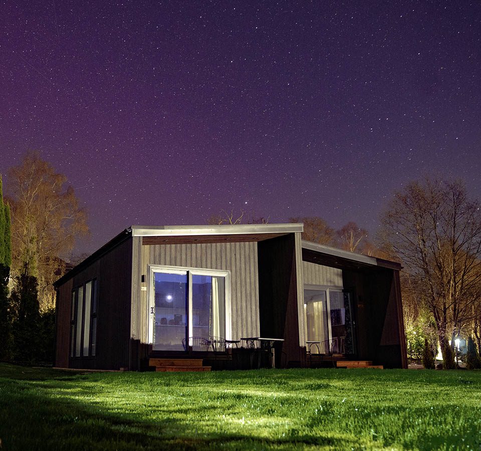 The exterior of a Studio Lodge at night with the Northern Lights in the sky at Loch Lomond Waterfront