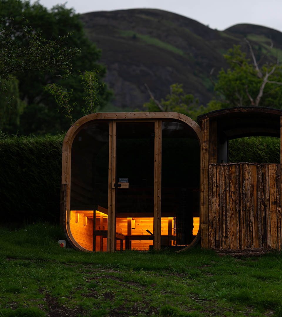 The exterior of the wild sauna at Loch Lomond Waterfont lit up in the evening.