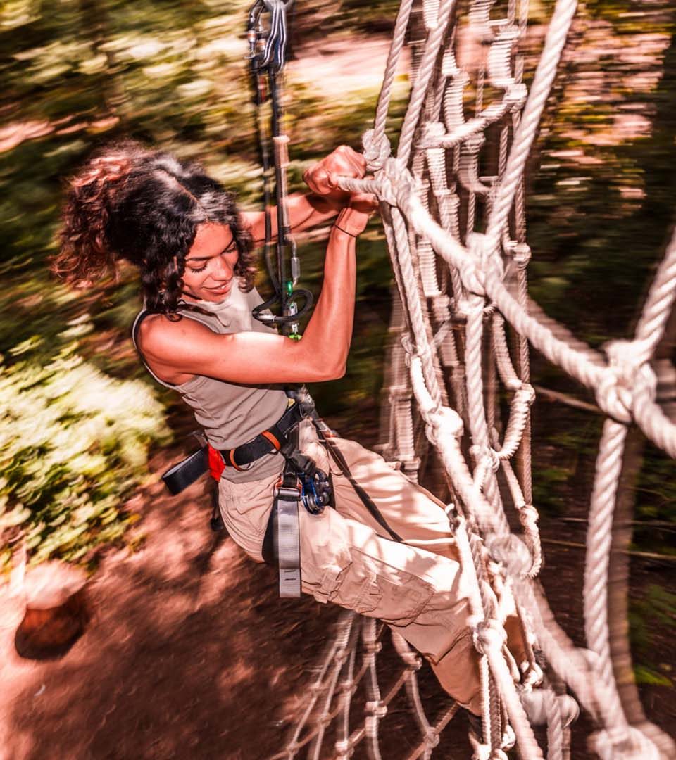 A girl climbing a rope climbing frame at Go Ape