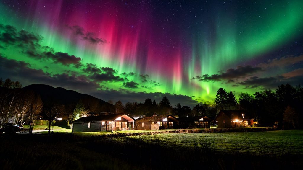 Loch Lomond Waterfront Lodges under spectacular Northern Lights in Winter.